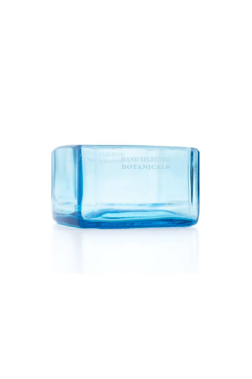 A square blue glass dip bowl seen from the side, with Hand Selected Botanicals lettering, on white