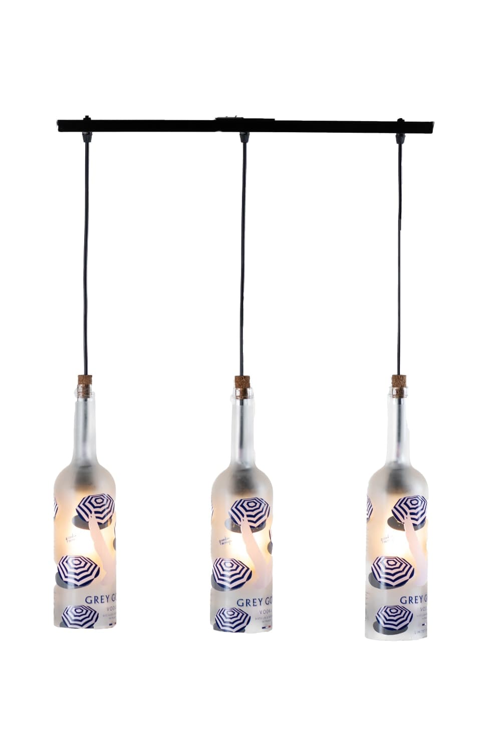 Three frosted glass bottles printed with blue and white beach umbrellas hang from a black rail on a white background
